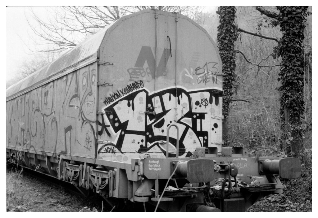 Schwarz-Weiß Bild eines abgestellten Güterwagons mit Grafitti